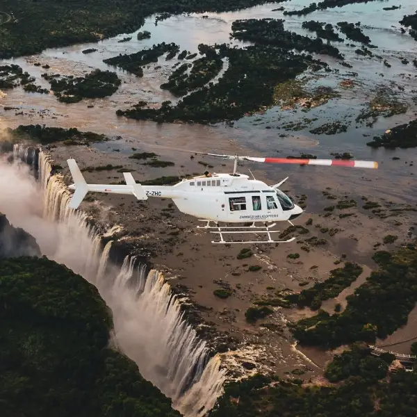 White helicopter flying alongside Victoria Falls